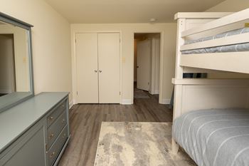 A bedroom with a bed, dresser, and wardrobe.at Chapel Valley Townhomes, Nottingham Maryland